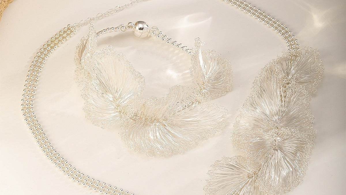 The Silver Ruffle Set laid flat, crocheted wire ruffles on a beaded chain.