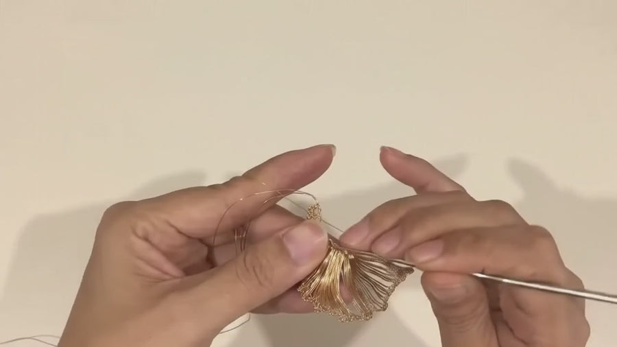 Hands drawing out a length of fine gold-tone wire