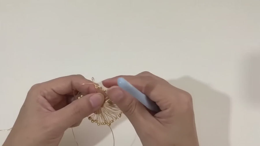 Hands pressing a crocheted wire piece into shape