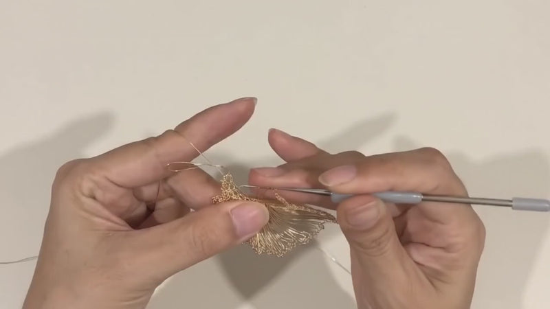 A small crochet hook pulling a loop of wire through the last one